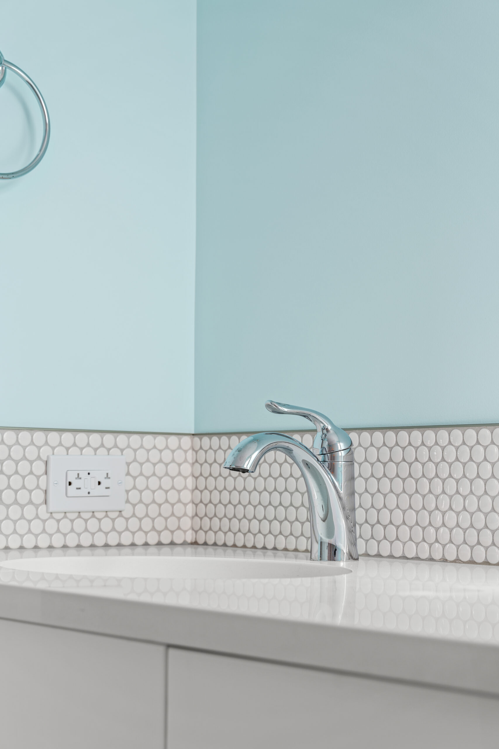 close up picture of bathroom sink tap, blue painted wall behind, white hexagon tile backsplash