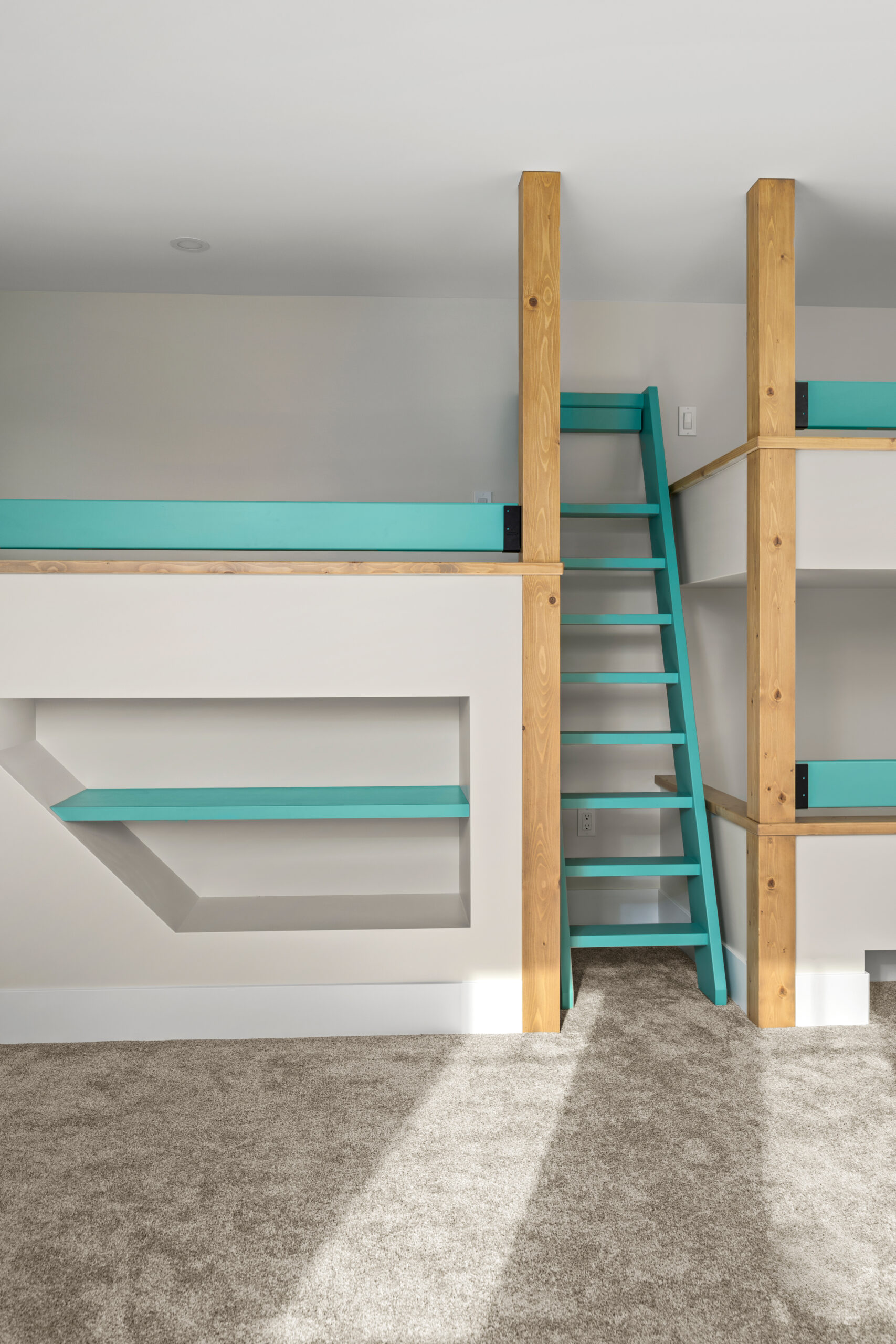 3 custom built bunk beds with a blue ladder between. There is a bookshelf under one bunk.