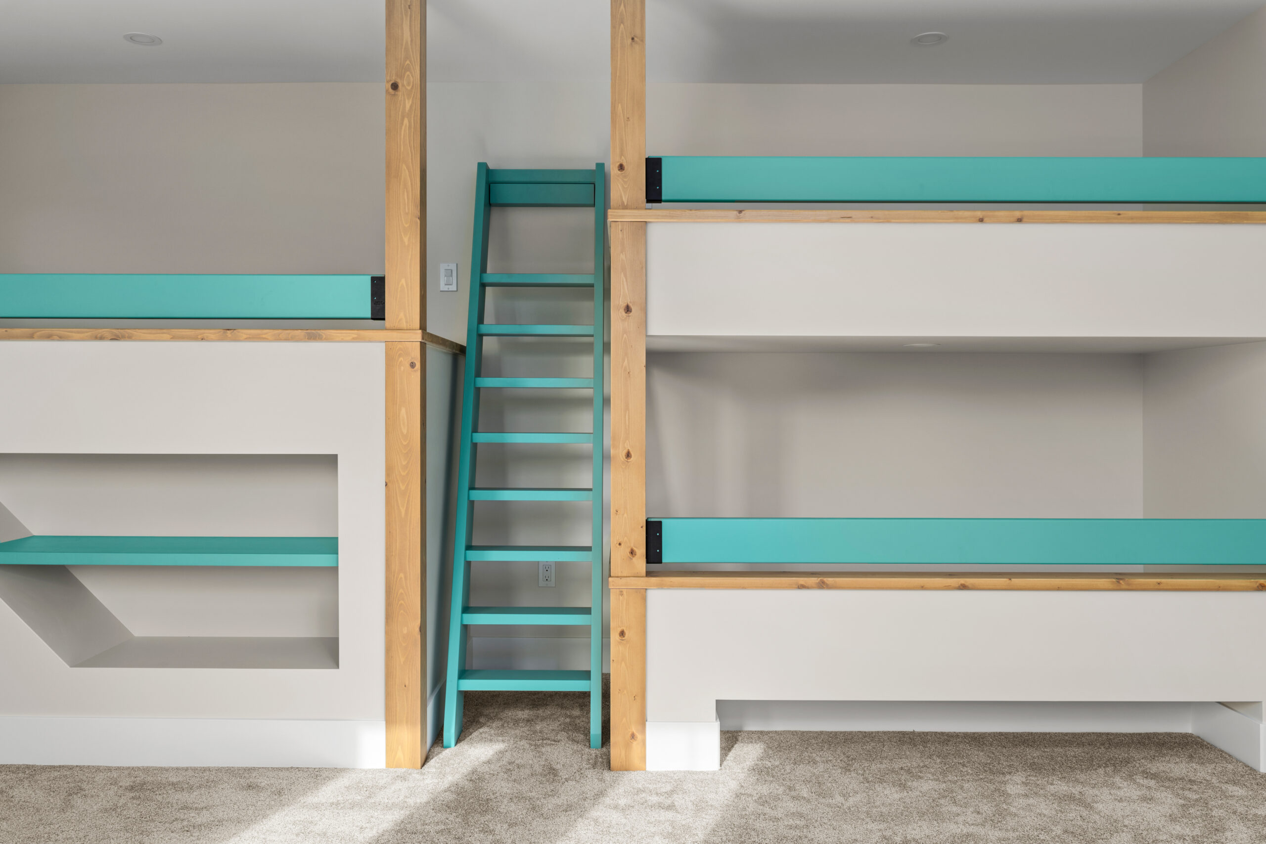 3 custom built bunk beds with a blue ladder between. There is a bookshelf under one bunk.