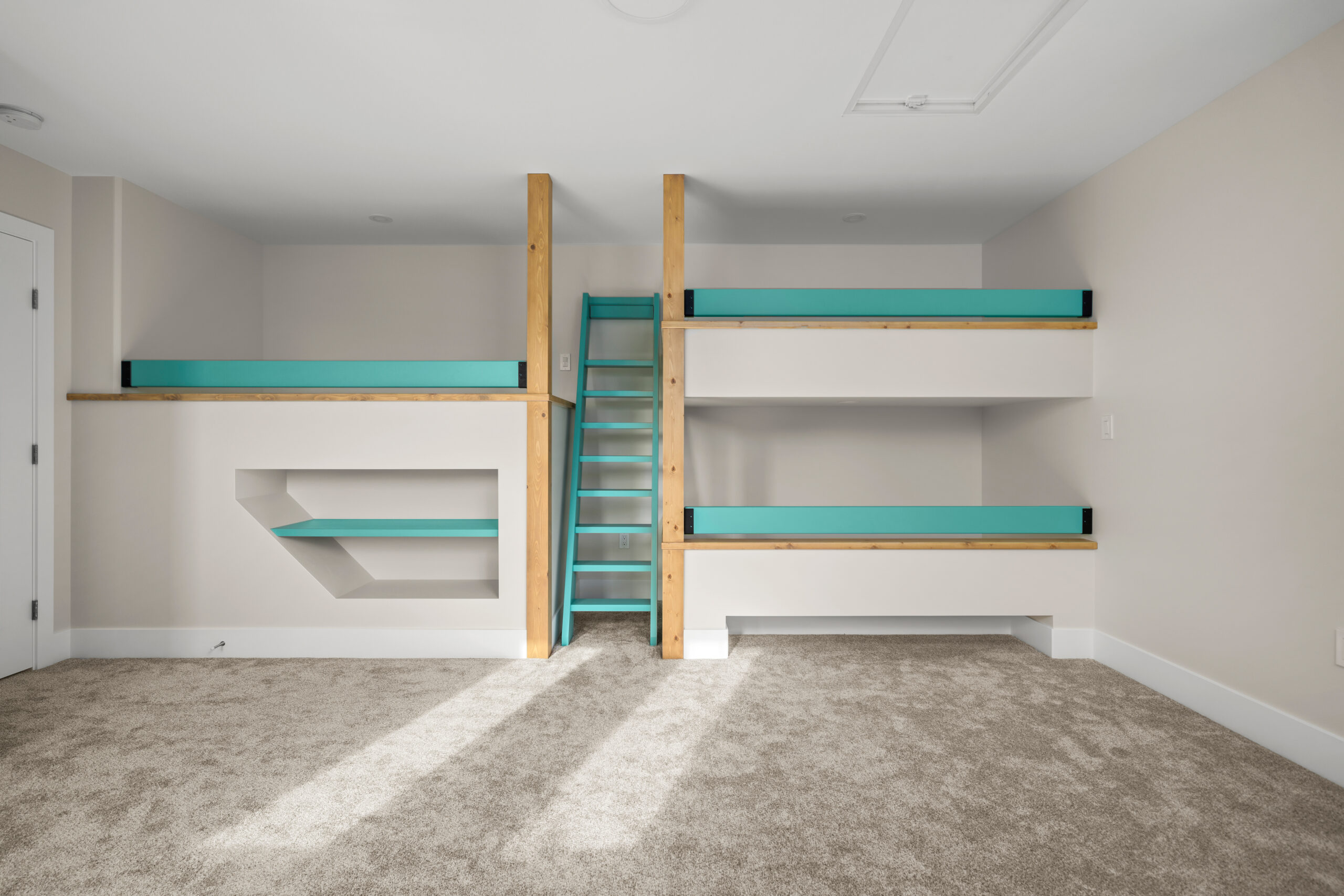 3 custom built bunk beds with a blue ladder between. There is a bookshelf under one bunk.