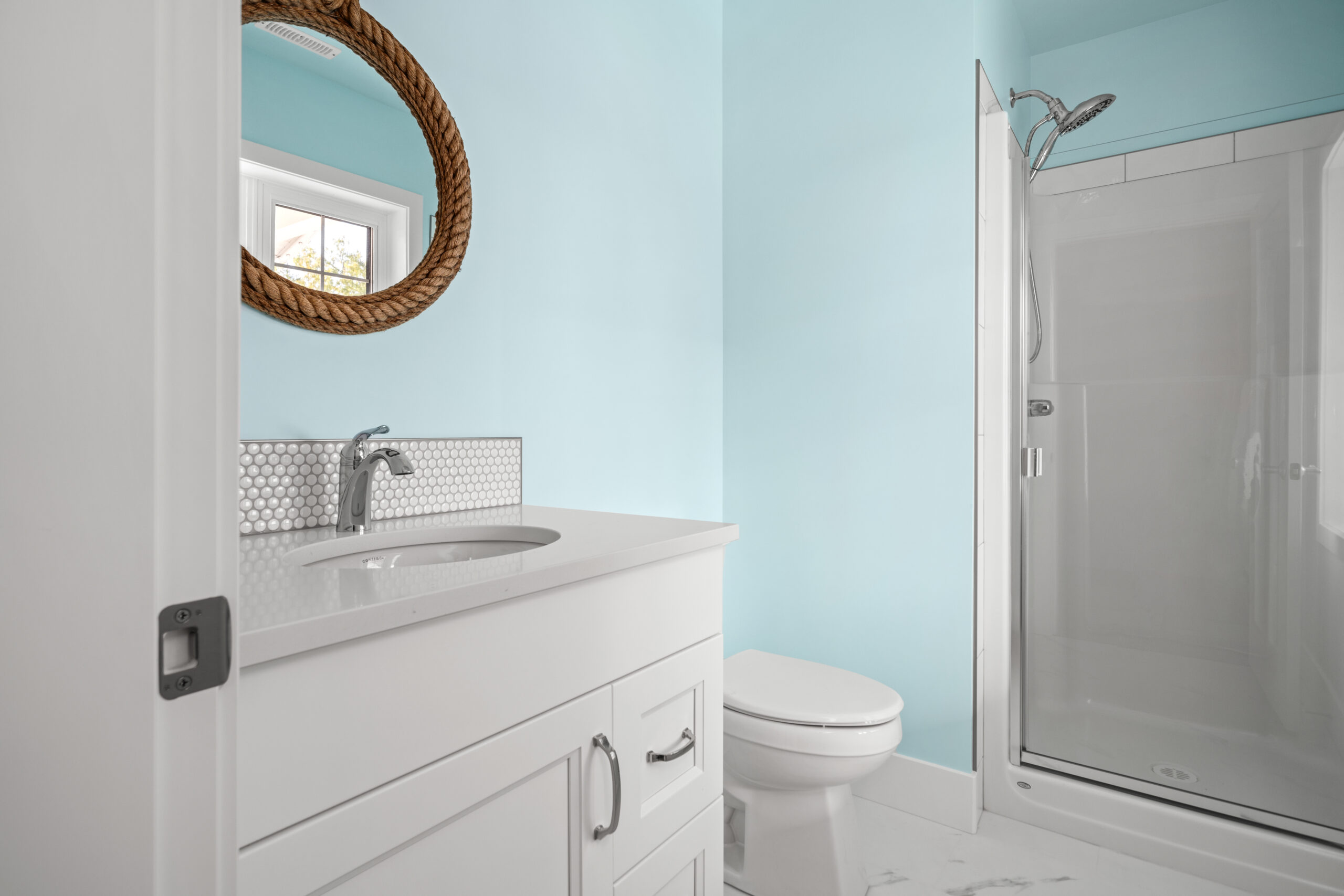 half bath vanity with rope-outlined circular mirror above the sink