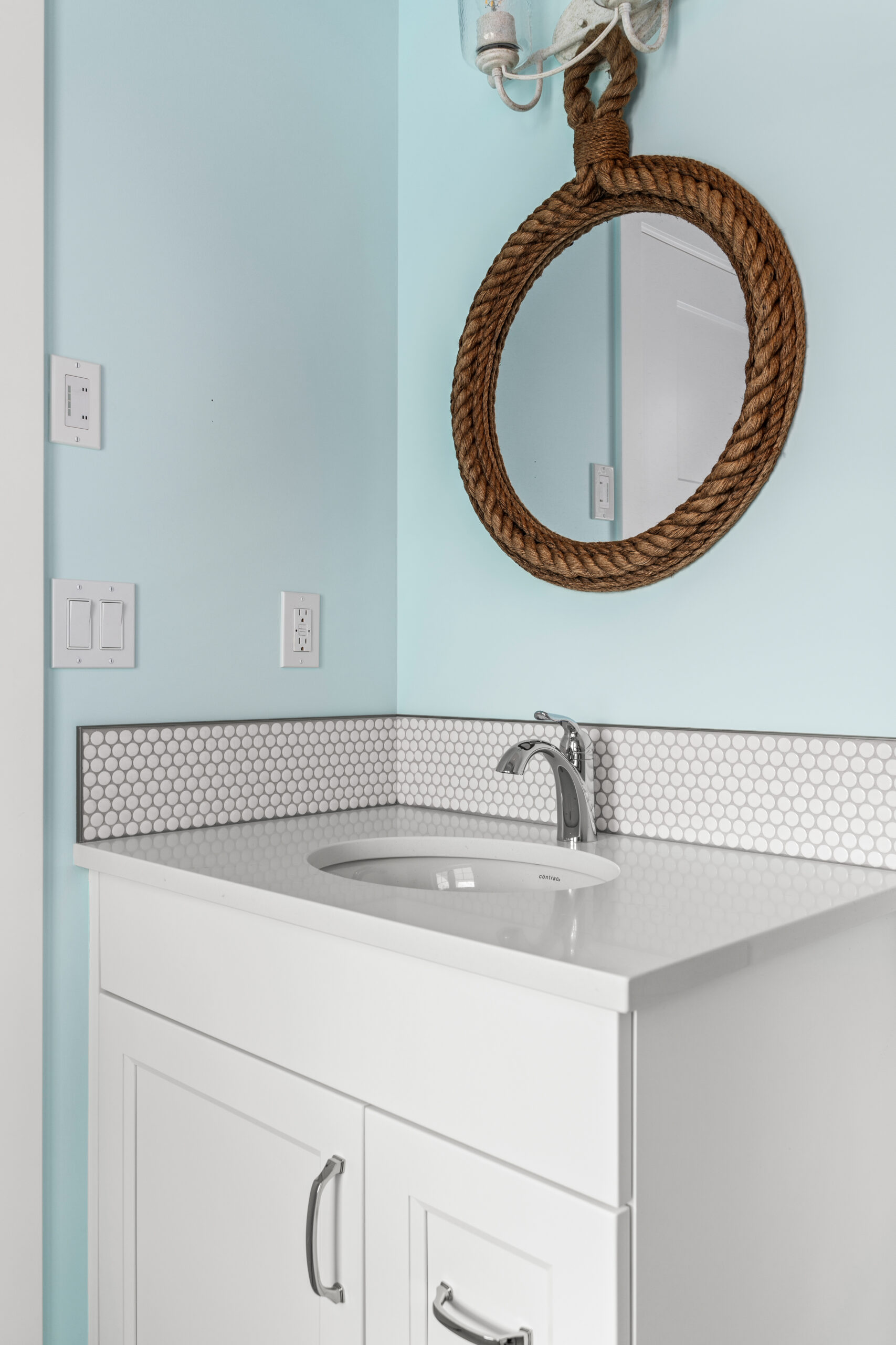 half bath vanity with rope-outlined circular mirror above the sink