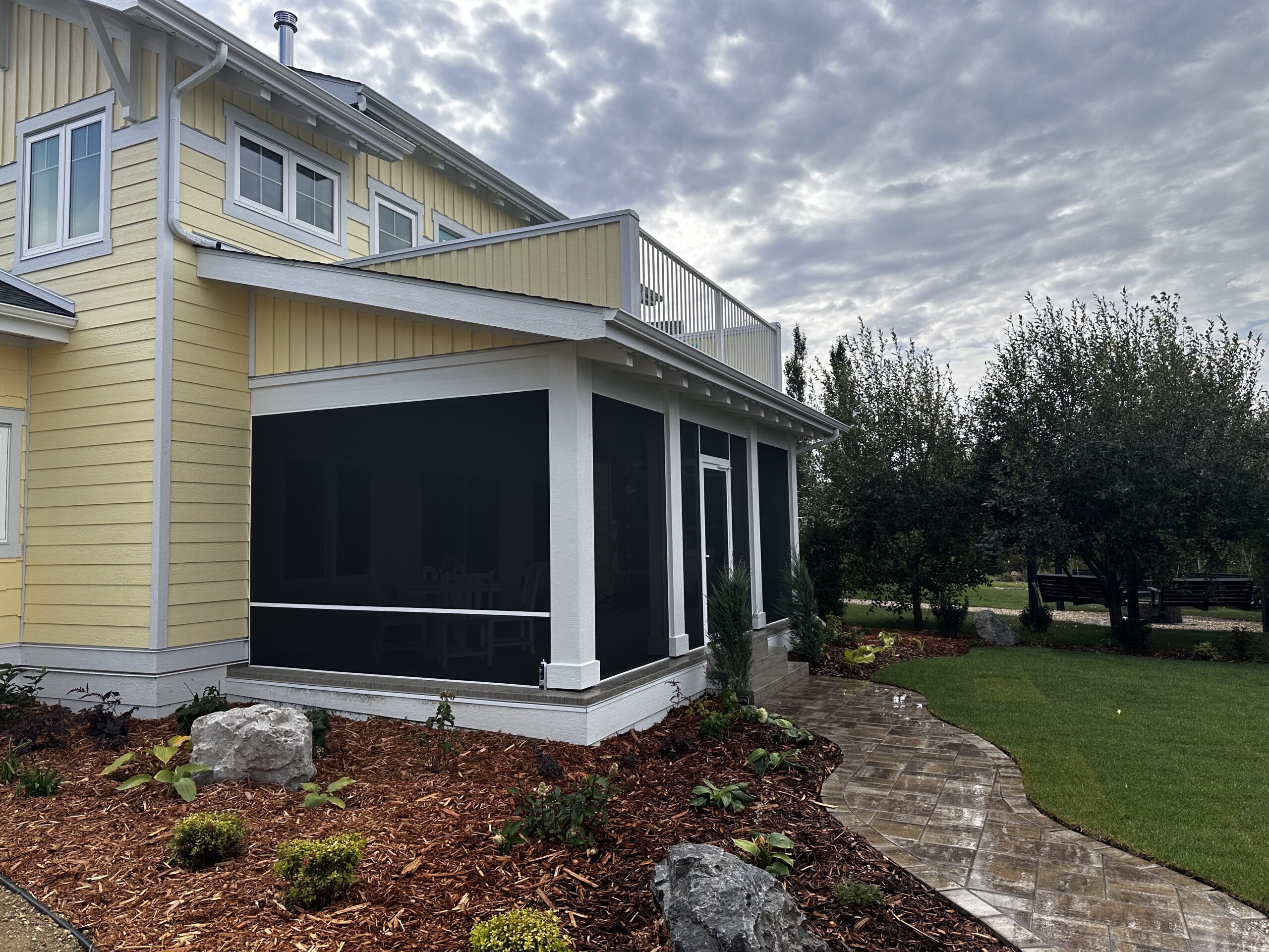 covered screened-in back deck on a yellow-sided home
