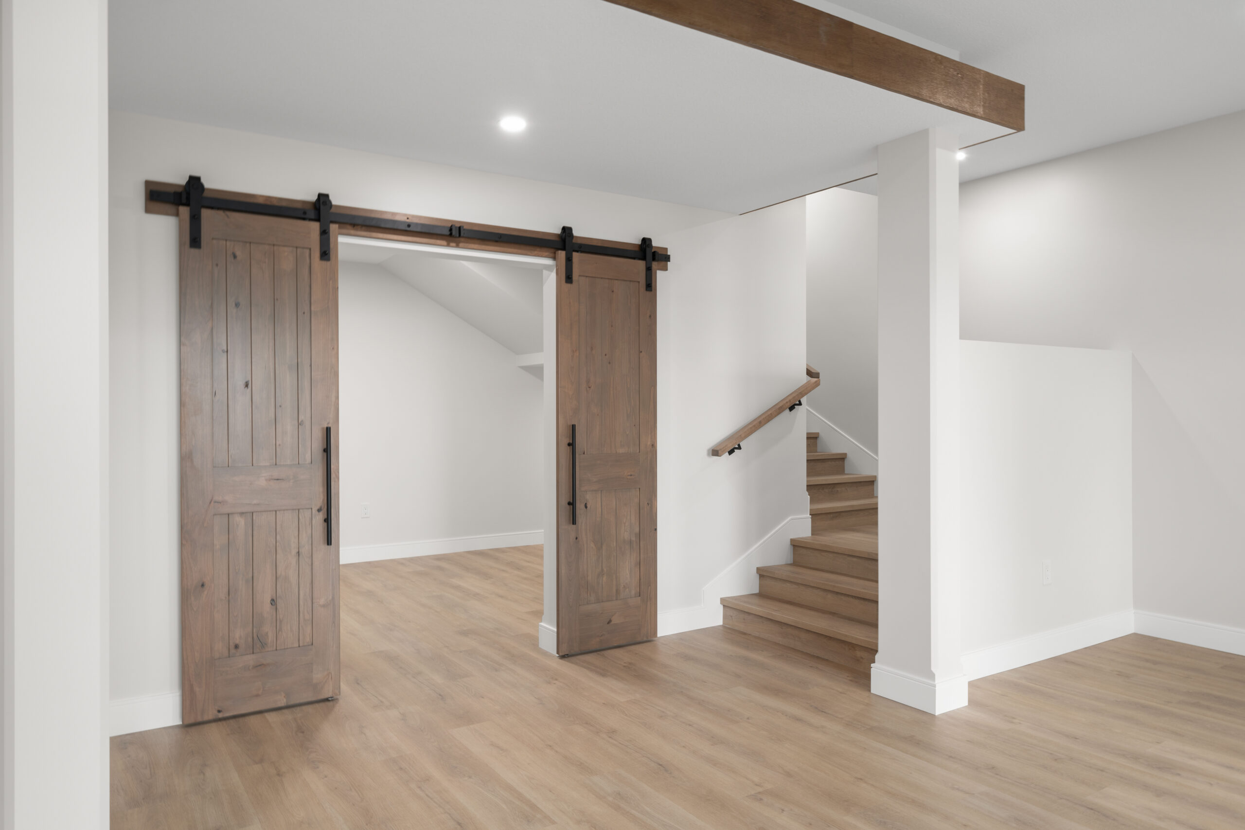 stairs leading down to walk-put basement and sliding barn doors into a flex room in a net zero home